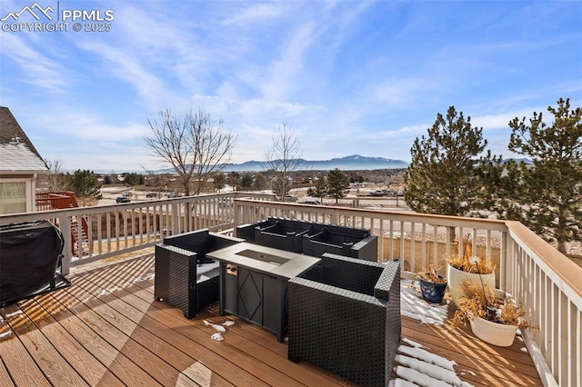 snow covered deck with a mountain view, a fire pit, and a grill