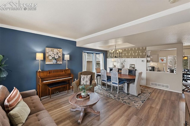 living room featuring crown molding, wood-type flooring, and a notable chandelier