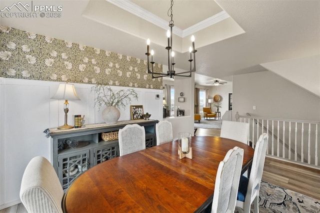 dining space with a raised ceiling, crown molding, ceiling fan with notable chandelier, and hardwood / wood-style floors