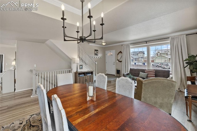 dining area featuring ornamental molding, a tray ceiling, light wood-type flooring, and a notable chandelier