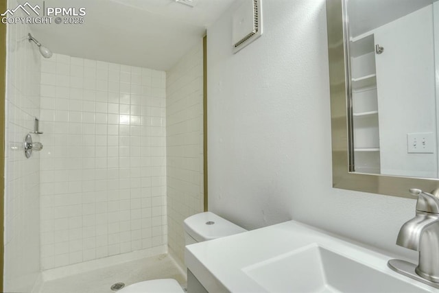 bathroom featuring vanity, a tile shower, and toilet