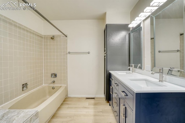 bathroom featuring hardwood / wood-style flooring, vanity, and tiled shower / bath combo