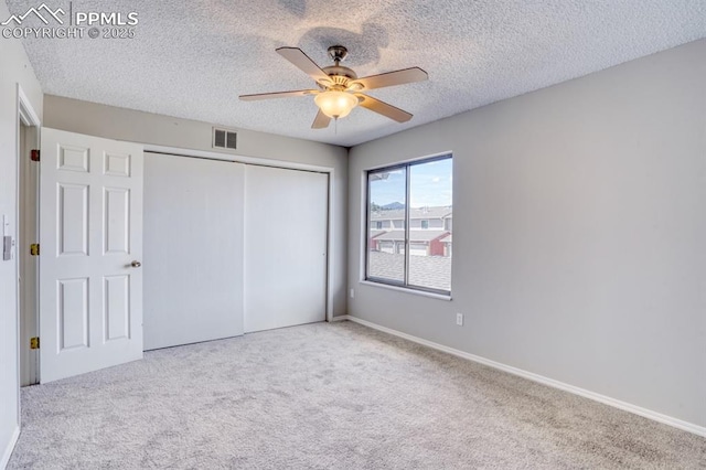 unfurnished bedroom with ceiling fan, light carpet, a textured ceiling, and a closet