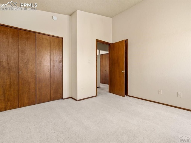 unfurnished bedroom with a closet, light carpet, and baseboards