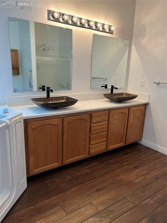 bathroom with vanity, washer / clothes dryer, wood-type flooring, and a shower with door