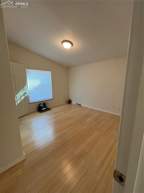 unfurnished room with vaulted ceiling and light hardwood / wood-style flooring