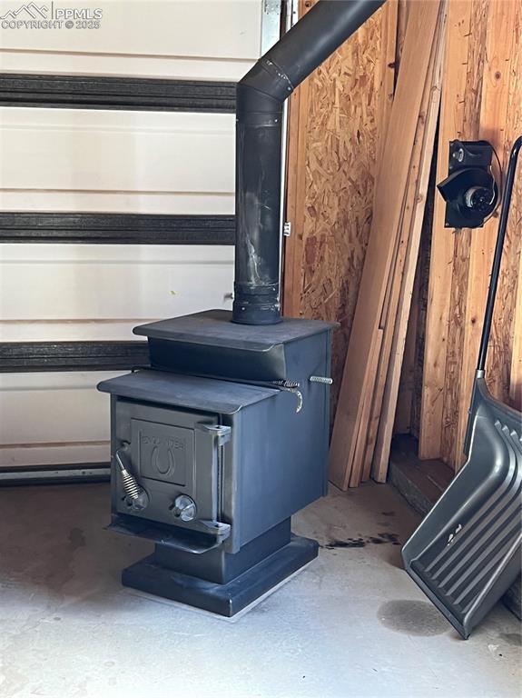 interior details with a wood stove, concrete floors, and wooden walls