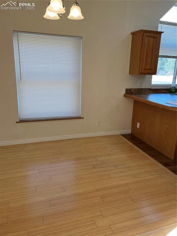 unfurnished dining area with a chandelier and light wood-type flooring