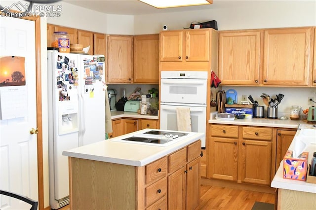 kitchen with white appliances, light hardwood / wood-style floors, and a center island