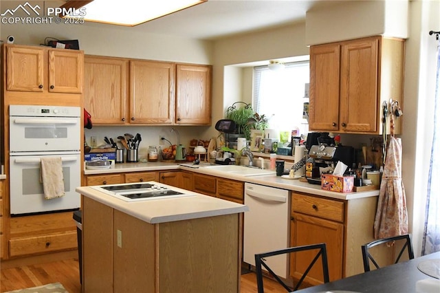 kitchen with white appliances, a center island, sink, and light wood-type flooring