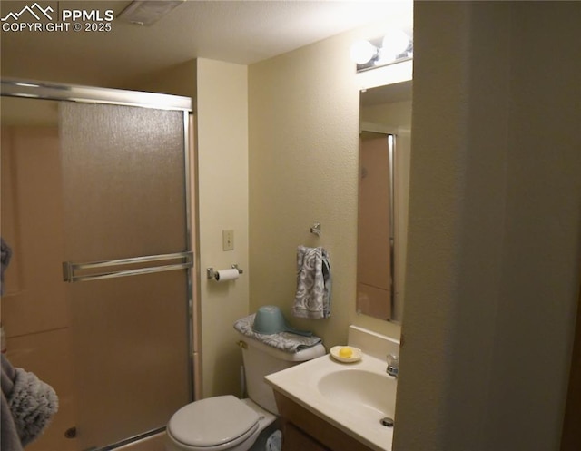 bathroom featuring vanity, a shower with shower door, and toilet