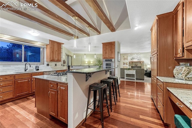 kitchen with a breakfast bar, sink, light stone counters, a center island, and pendant lighting