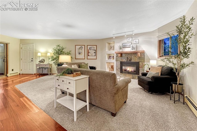 living room featuring baseboard heating, track lighting, a textured ceiling, and light wood-type flooring