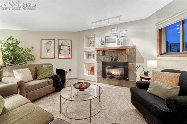 carpeted living room featuring rail lighting, built in features, and a fireplace