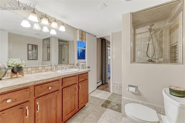 bathroom with tiled shower, toilet, a textured ceiling, a baseboard radiator, and vanity