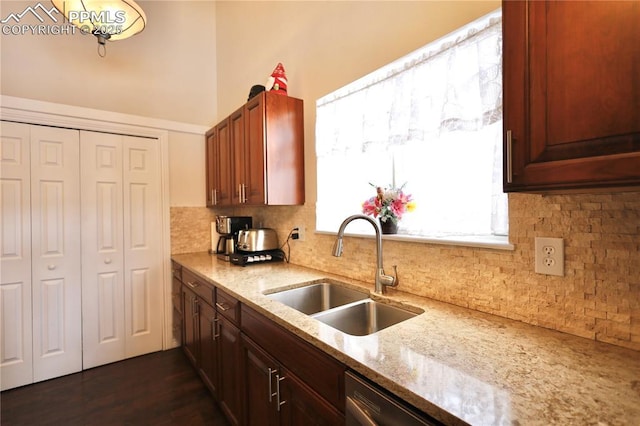 kitchen featuring dark wood-style floors, light stone counters, a sink, and tasteful backsplash