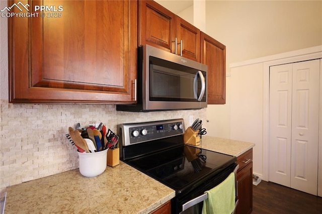 kitchen featuring light countertops, brown cabinetry, decorative backsplash, electric range oven, and stainless steel microwave