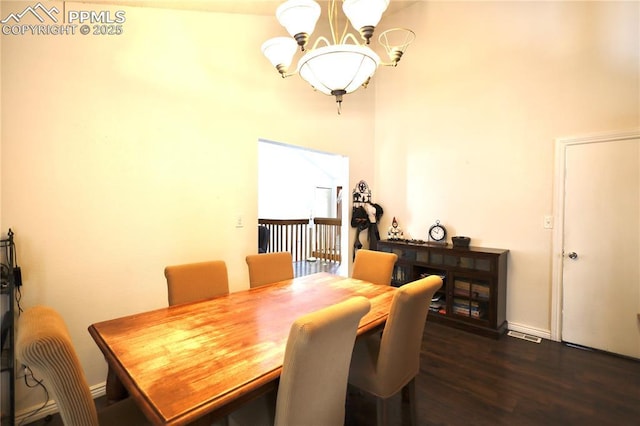 dining area with baseboards, dark wood finished floors, and an inviting chandelier