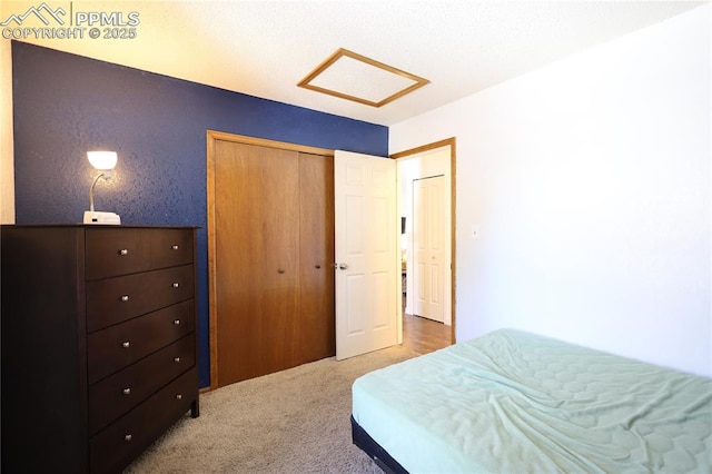 bedroom with light carpet, a closet, and attic access