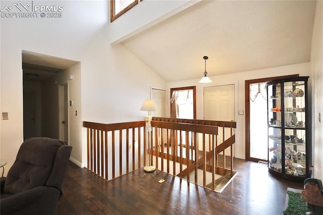 corridor with lofted ceiling, dark wood-style floors, baseboards, and an upstairs landing