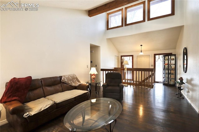 living area with dark wood-style floors, beamed ceiling, and a towering ceiling