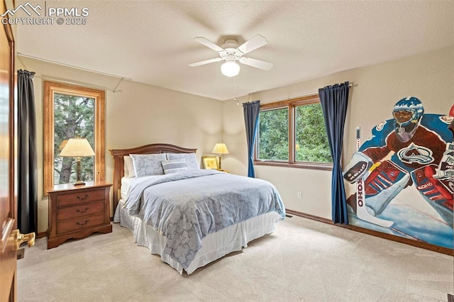 bedroom with ceiling fan, light colored carpet, baseboards, and a textured ceiling