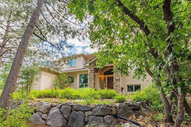 view of front of property featuring stone siding and stucco siding