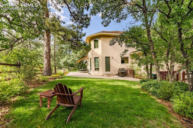 back of property with stucco siding, a patio, a lawn, and fence