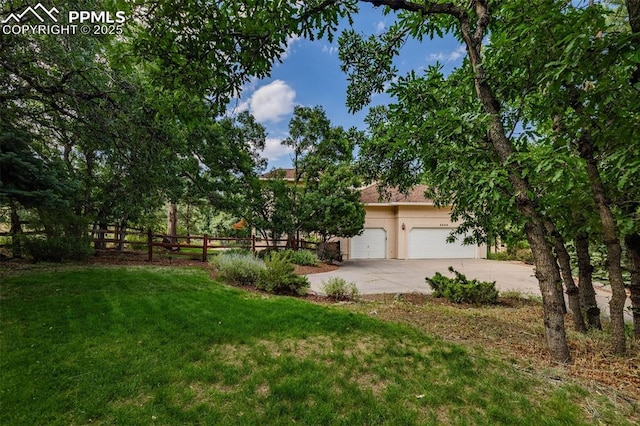 view of front of house featuring an attached garage, fence, a front yard, stucco siding, and driveway