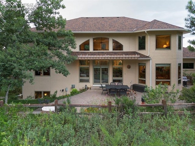 back of house featuring stucco siding, a shingled roof, and a patio