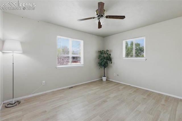 spare room featuring wood finished floors, baseboards, a ceiling fan, and visible vents