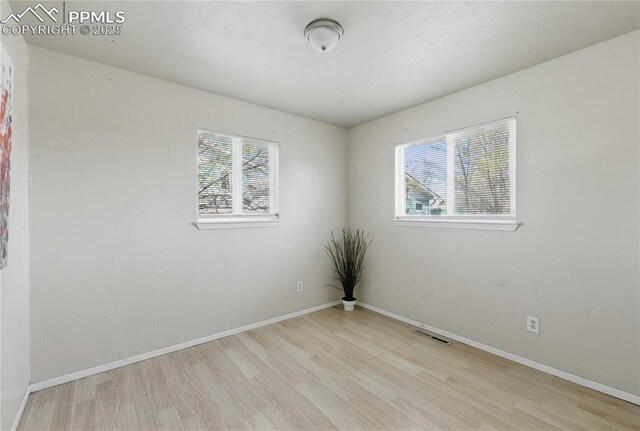 unfurnished room featuring light wood-style flooring, baseboards, and visible vents
