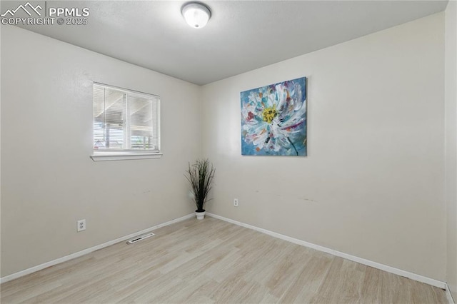 empty room featuring visible vents, baseboards, and wood finished floors