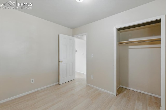 unfurnished bedroom with a closet, baseboards, and wood finished floors