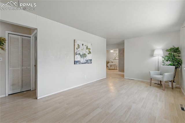 living area featuring light wood finished floors, visible vents, and baseboards