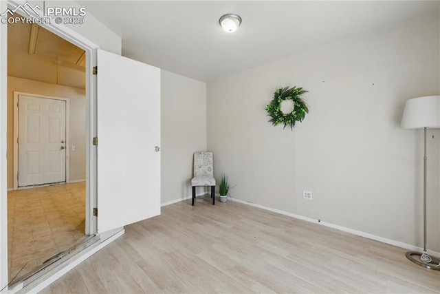 spare room featuring baseboards, attic access, and wood finished floors