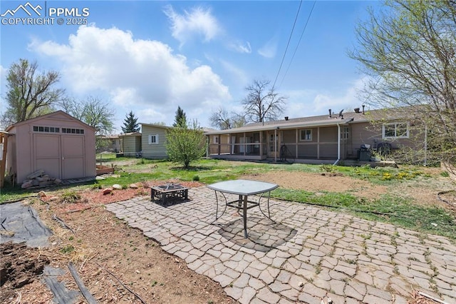 back of property with a patio area, an outbuilding, an outdoor fire pit, a sunroom, and a storage unit