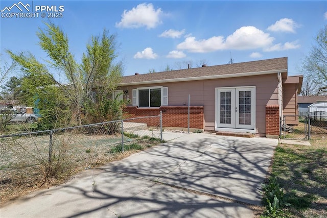 back of house featuring brick siding, french doors, fence private yard, and a gate