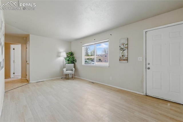 interior space featuring baseboards and light wood finished floors
