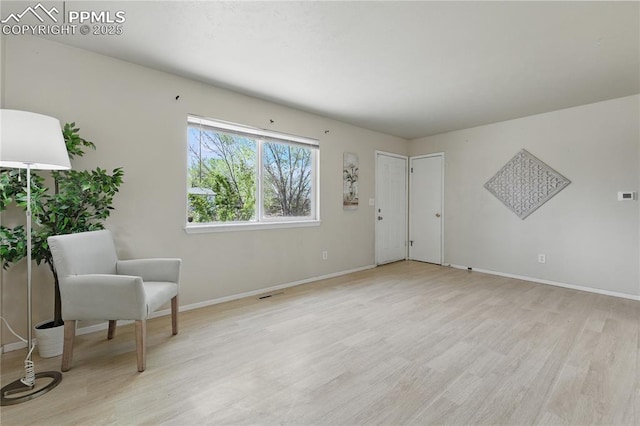unfurnished room with light wood finished floors, visible vents, and baseboards