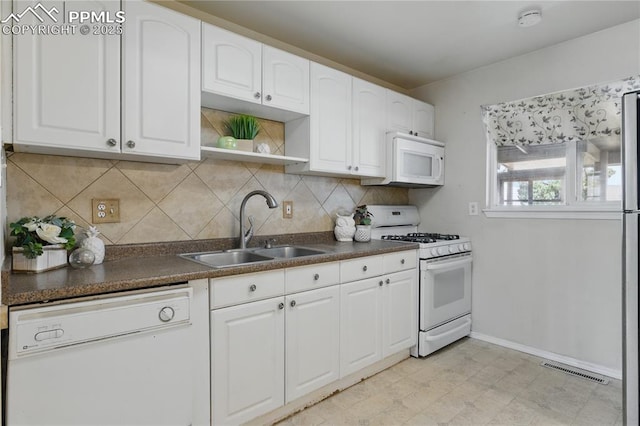 kitchen featuring visible vents, open shelves, a sink, dark countertops, and white appliances