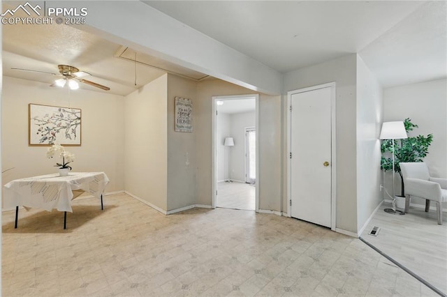 living area featuring attic access, baseboards, a ceiling fan, and light floors