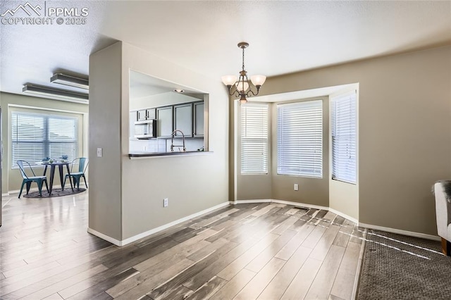 unfurnished dining area featuring sink, hardwood / wood-style floors, and a notable chandelier