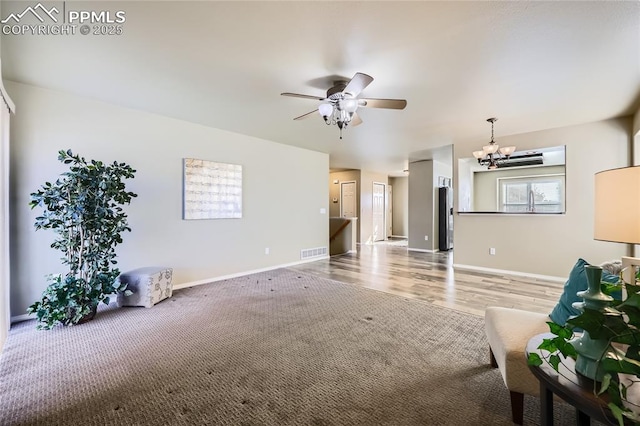 carpeted living room with ceiling fan with notable chandelier