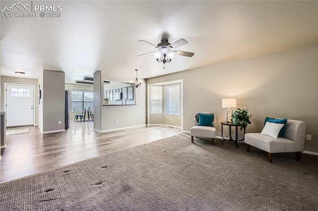 sitting room featuring hardwood / wood-style flooring and ceiling fan with notable chandelier