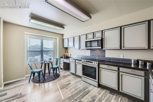 kitchen with gray cabinetry, backsplash, light hardwood / wood-style flooring, and stainless steel appliances