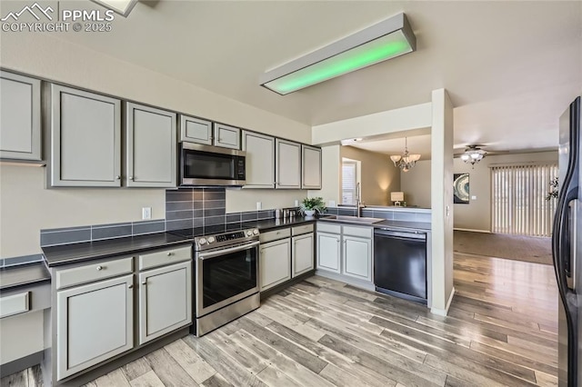 kitchen with gray cabinetry, sink, light wood-type flooring, and appliances with stainless steel finishes