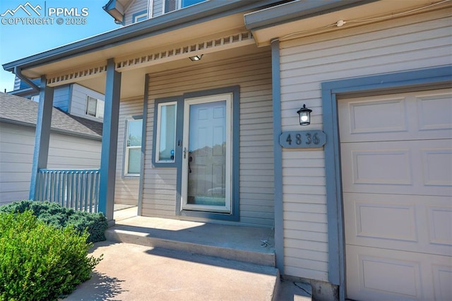 view of exterior entry with a garage and covered porch