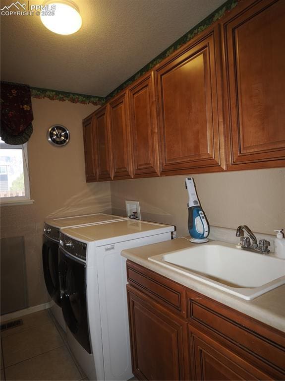 clothes washing area featuring washer and dryer, sink, cabinets, tile patterned flooring, and a textured ceiling