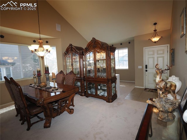 carpeted dining space with a notable chandelier and high vaulted ceiling